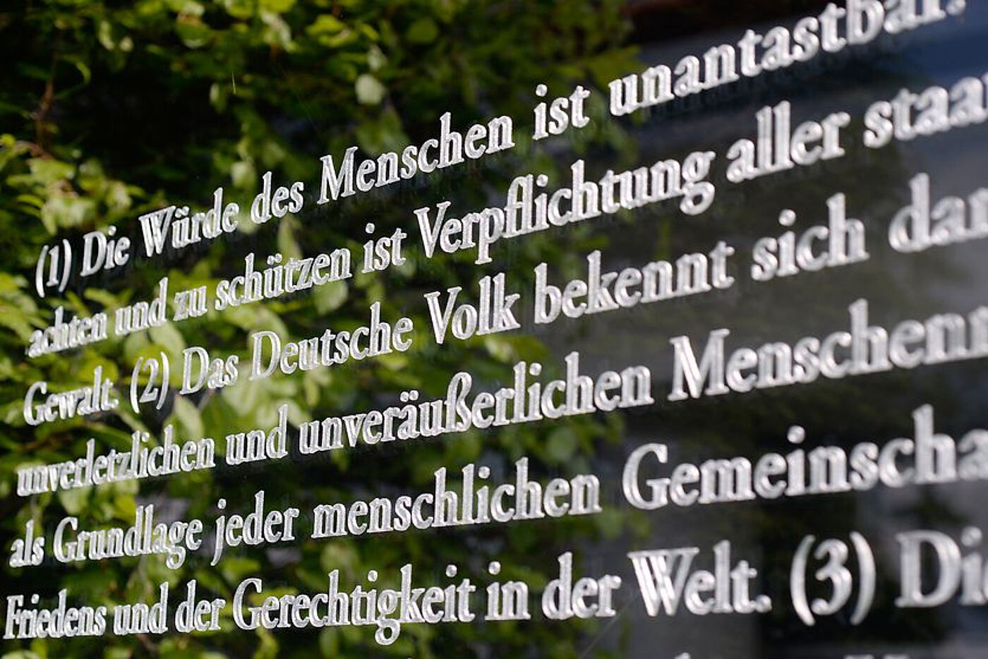 Artikel 1 des deutschen Grundgesetzes in weißer Farbe auf einer Scheibe.