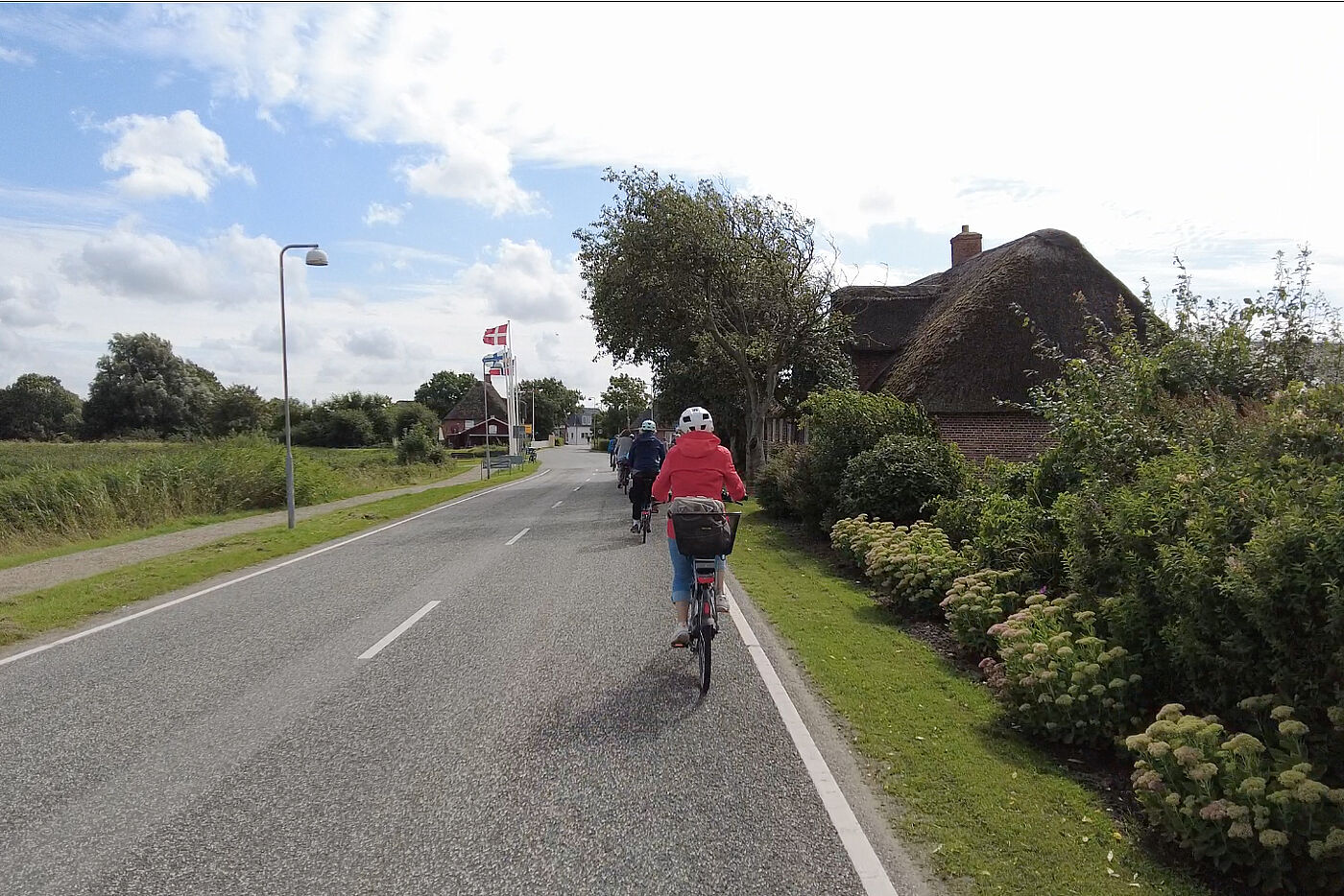 Eine kleine Gruppe von Radfahrerinnen fährt auf der Straße in Richtung des deutsch-dänischen Grenzüberganges.